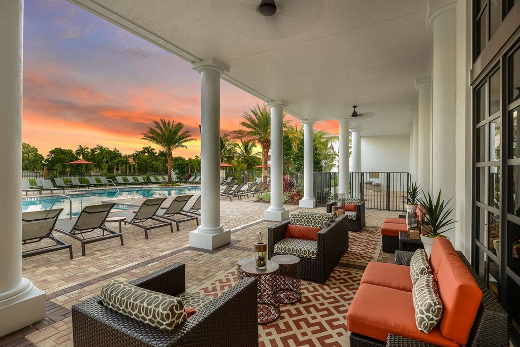 Covered veranda seating by the pool at Palm Ranch Apartments in Davie, FL