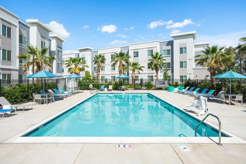 A large swimming pool in front of apartment buildings.