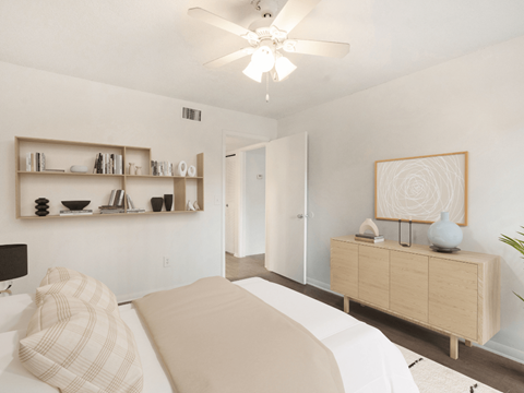 A bedroom with a bed, a dresser, and a ceiling fan.