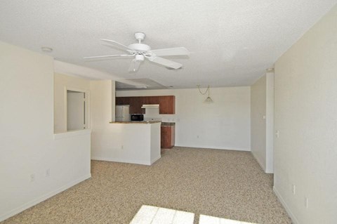 an empty living room and kitchen with a ceiling fan