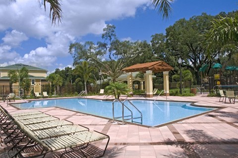 a swimming pool with chairs and trees in the background