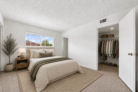 A bedroom with a bed, nightstand, and a window.