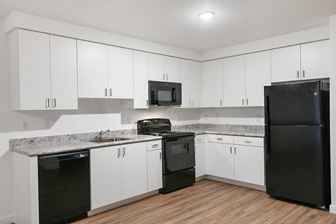 an empty kitchen with white cabinets and black appliances