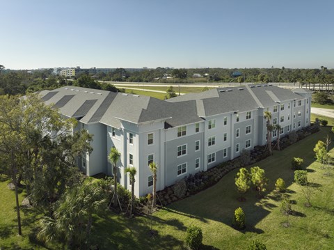 an aerial view of a white building with gray roofs