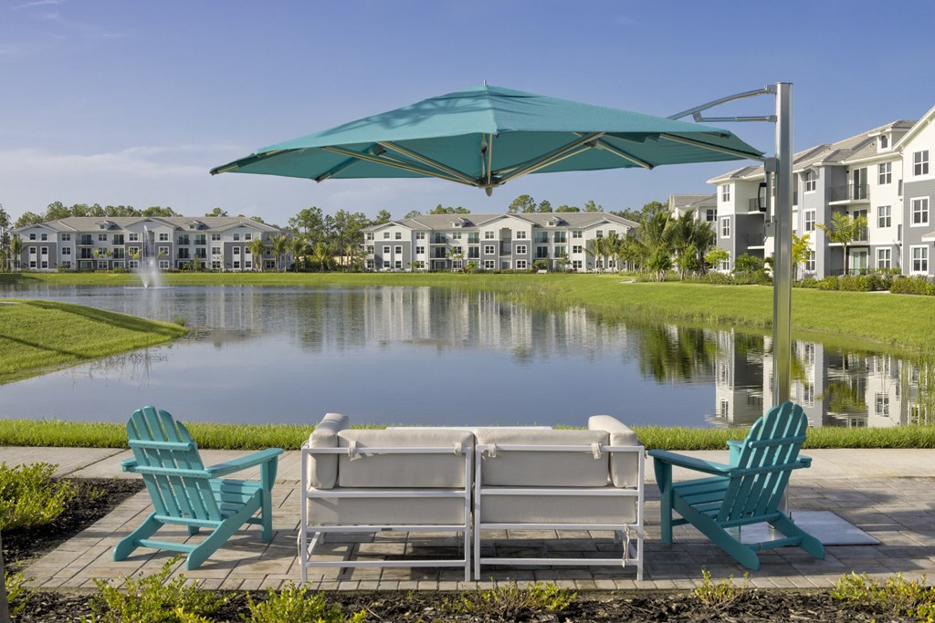 Lakeside Seating with Chairs and an Umbrella at Everly Apartments in Naples, FL