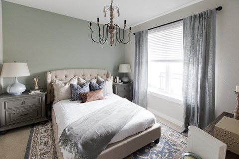 a bedroom with a bed and a chandelier    and a window