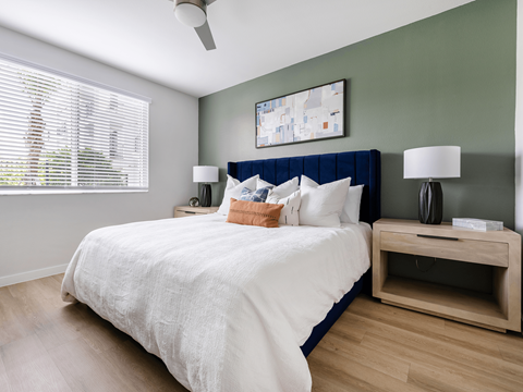 A bedroom with a bed, nightstand, and a painting on the wall.
