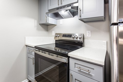 A modern kitchen with a stainless steel refrigerator and a white countertop.