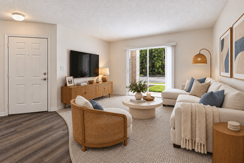 A living room with a white couch, a wicker chair, and a flat screen TV.