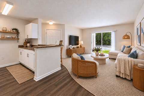 A well-lit, spacious living room with a kitchen area in the background.