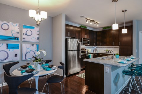 A kitchen with a table set for two and a refrigerator in the background.