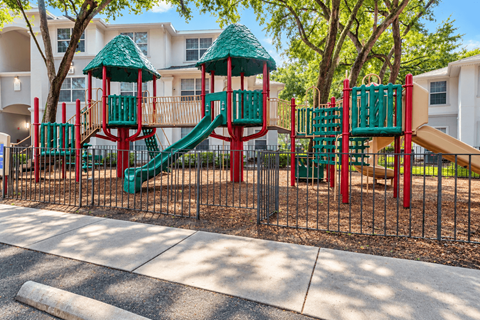 A playground with a red and green slide and a green and red structure.
