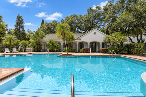 A swimming pool in front of a house surrounded by trees.