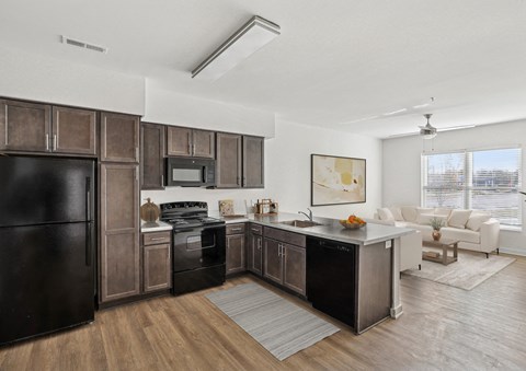 A modern kitchen with dark brown cabinets and black appliances.