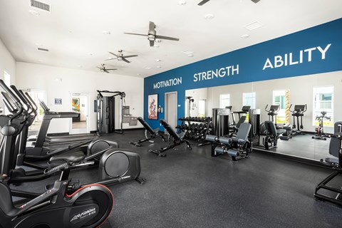A gym with a variety of equipment and a wall that says "ABILITY".