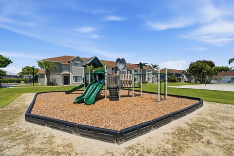 A playground with a green slide and a brown sandbox.