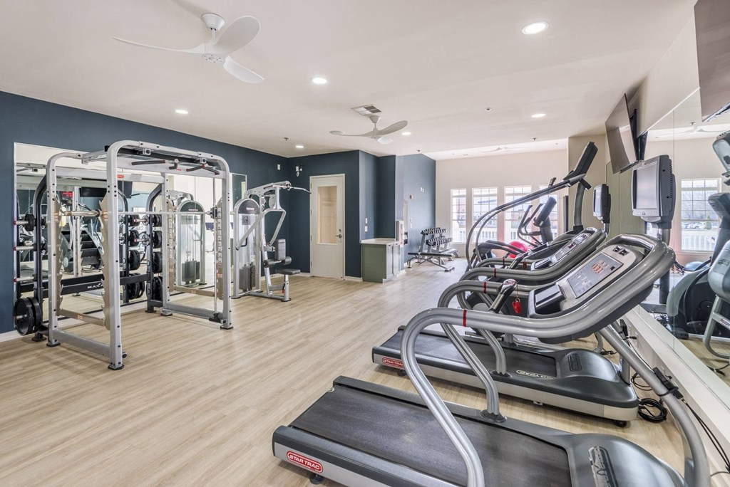 a gym with cardio equipment and a window