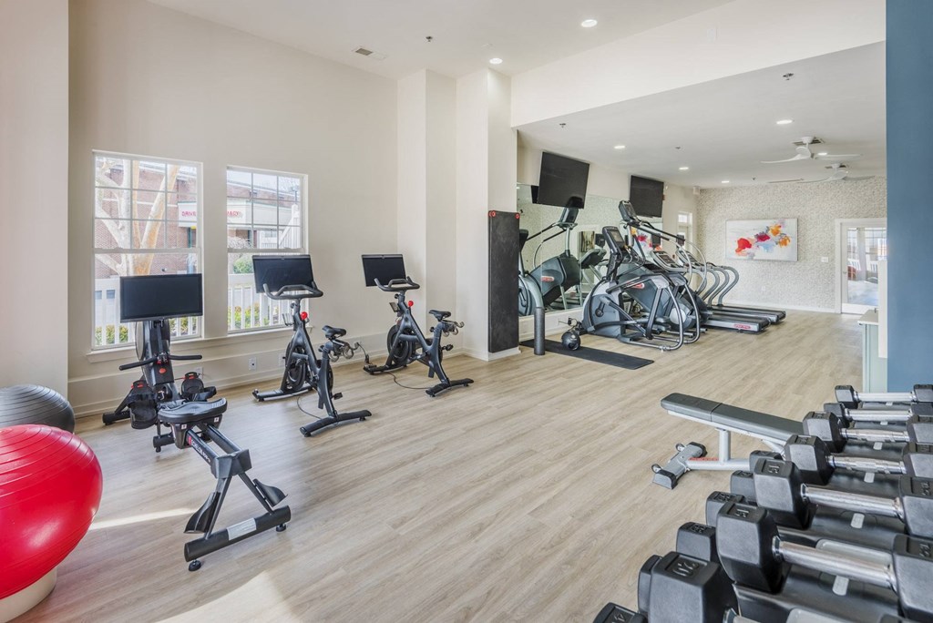 a gym with cardio equipment and weights on the floor