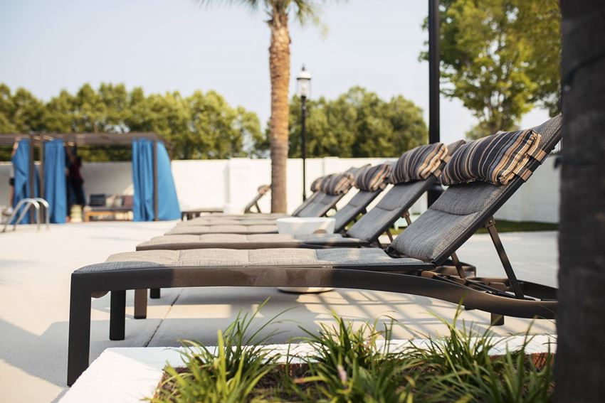 a row of lounge chairs on a patio near a pool