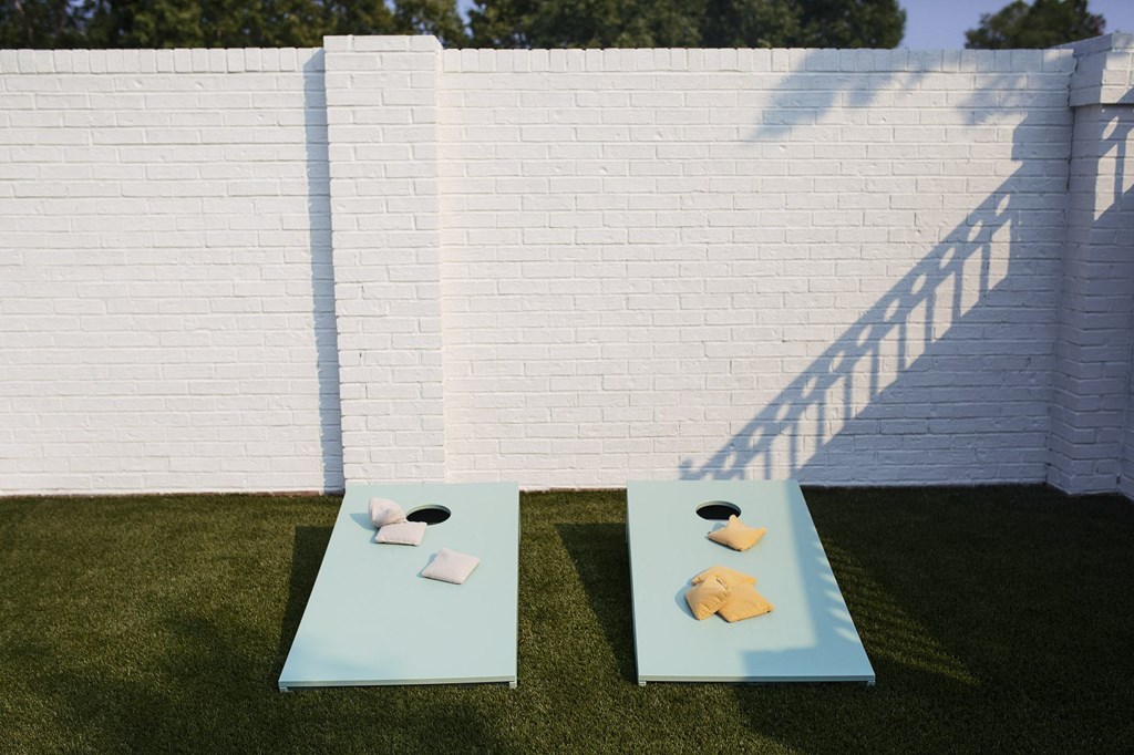 two tables on the grass in front of a white wall