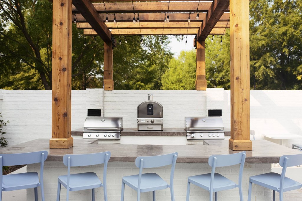 a patio with blue chairs and a barbecue grill