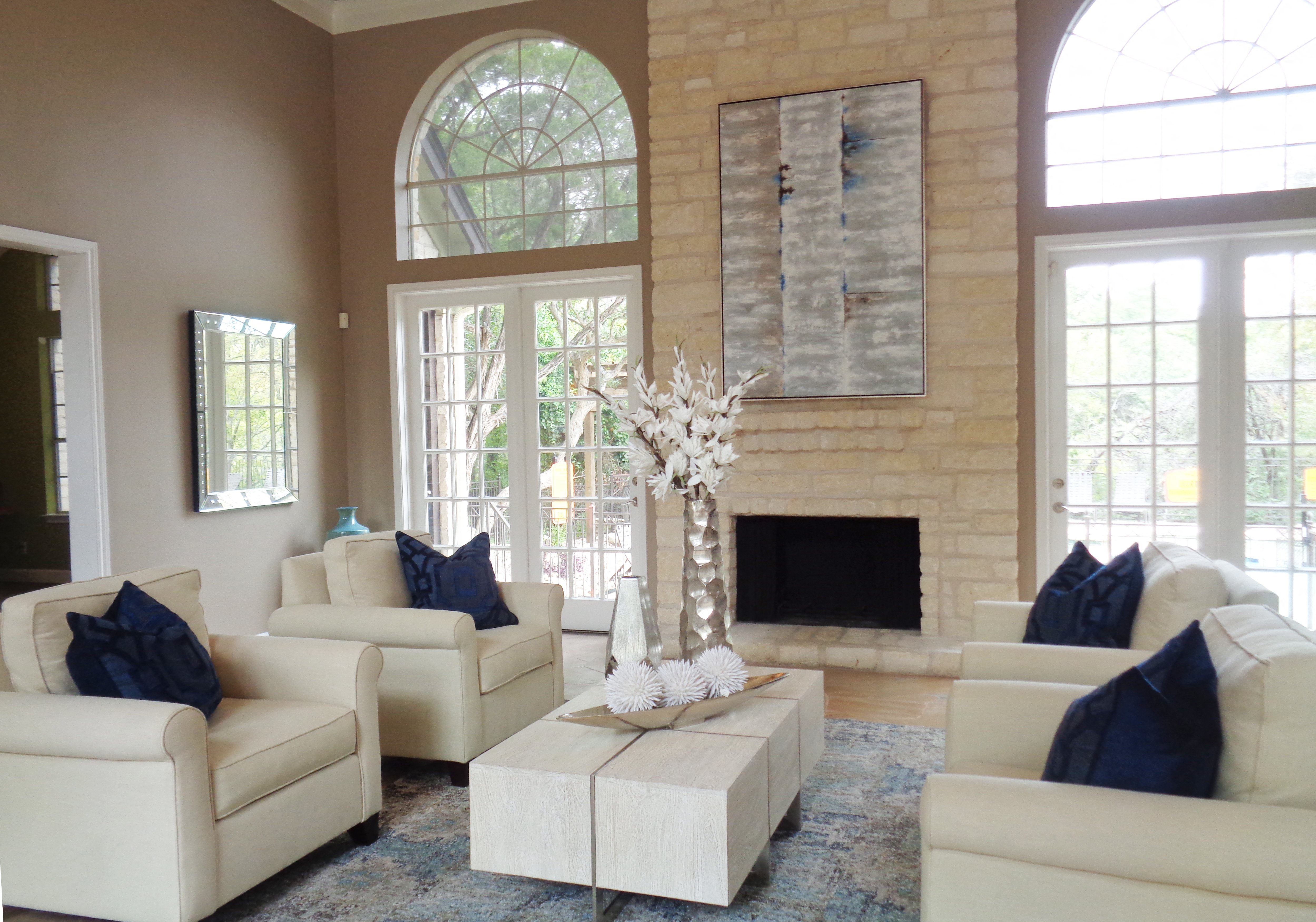 a living room with white furniture and a stone fireplace