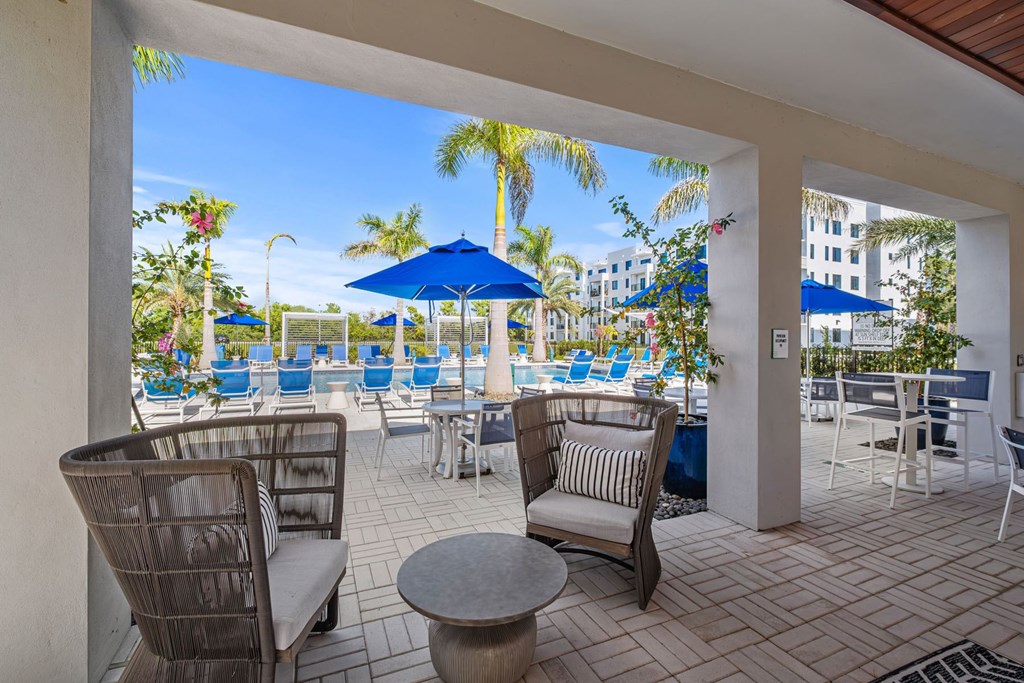 A patio with chairs and a table overlooking a pool.