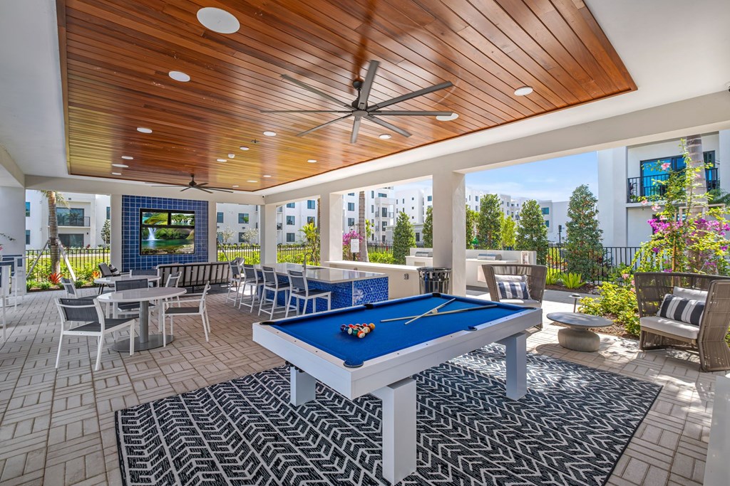A pool table is in the middle of a patio with a blue cloth on it.