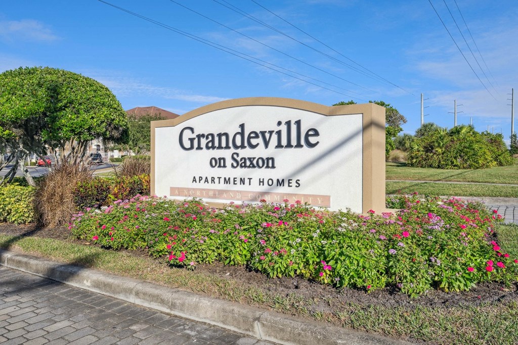a sign on saxon apartment homes in front of flowers at Grandeville on Saxon, Orange City, FL, 32763
