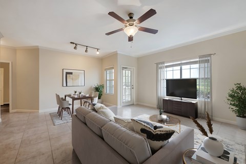 A living room with a grey couch and a ceiling fan.