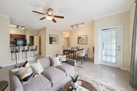 A living room with a grey couch and a ceiling fan.