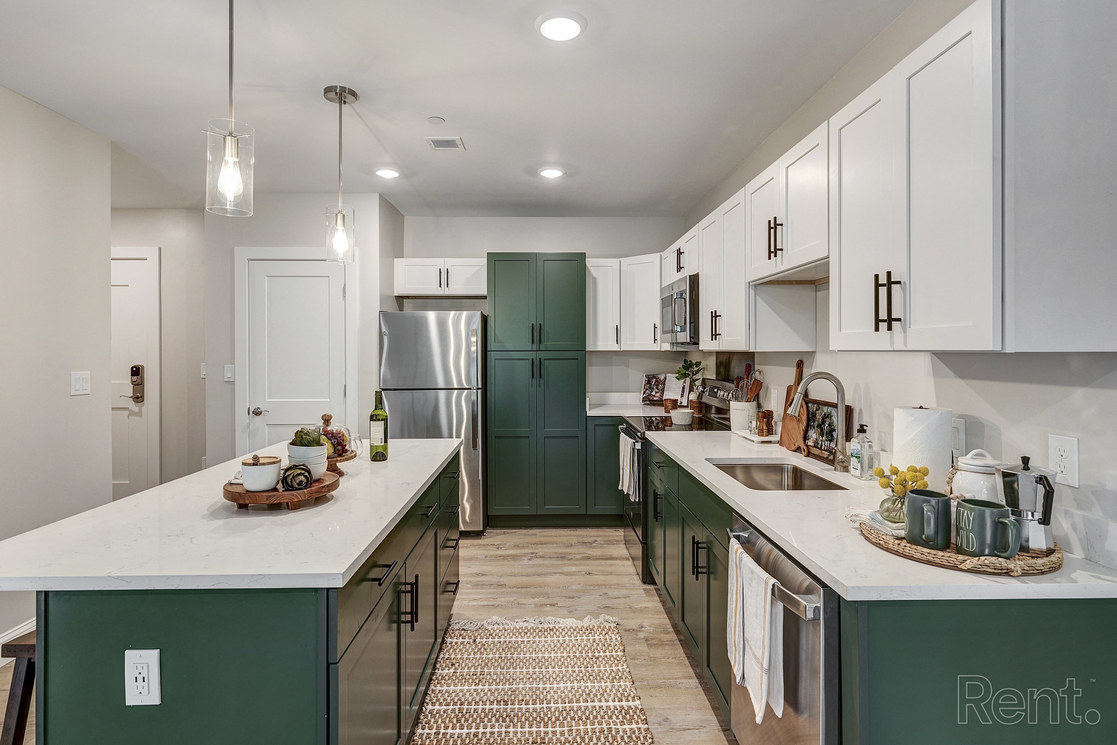 a kitchen with green cabinets and white counters and a stainless steel refrigerator at Edgebrook Residences, Merrimack, NH 03054