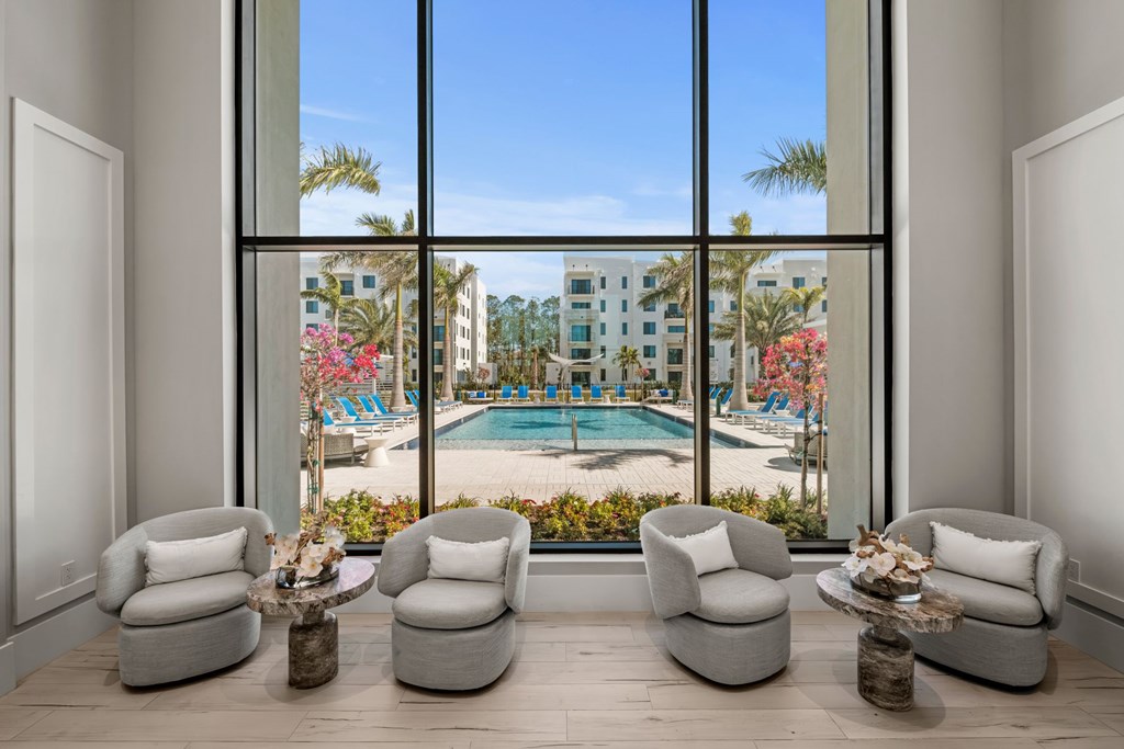 A room with a view of a pool and buildings outside the window.