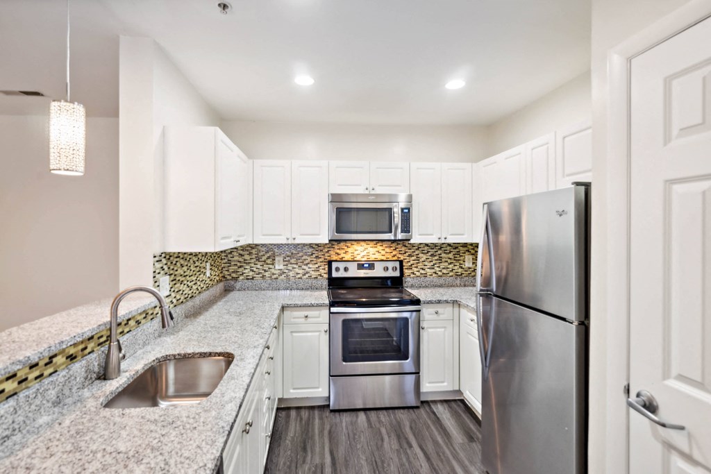 a kitchen with stainless steel appliances and white cabinets at Highlands at Faxon Woods, Quincy, 02169
