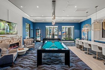 A billiard table is in the middle of a room with a pool table chair and a pool table.