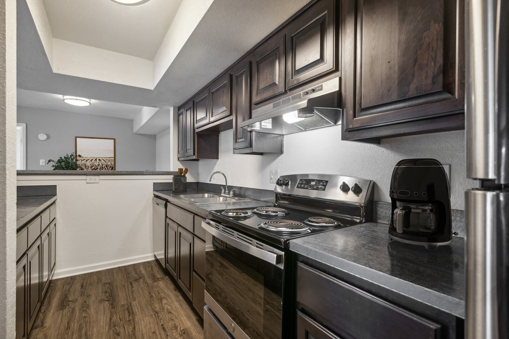 A modern kitchen with dark wood cabinets and stainless steel appliances.