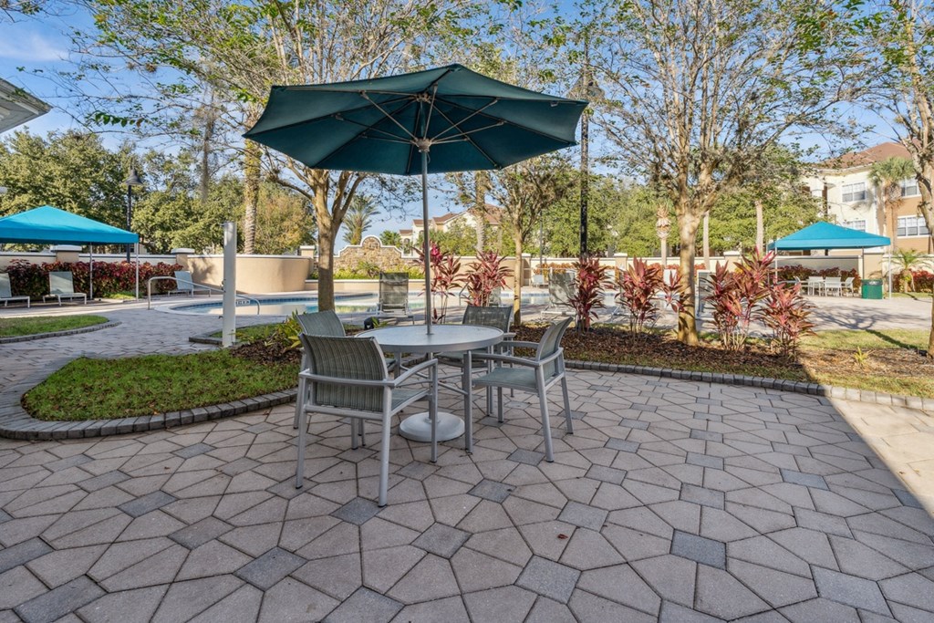 a pool patio with a table and chairs and an umbrella at Grandeville on Saxon, Orange City, Florida