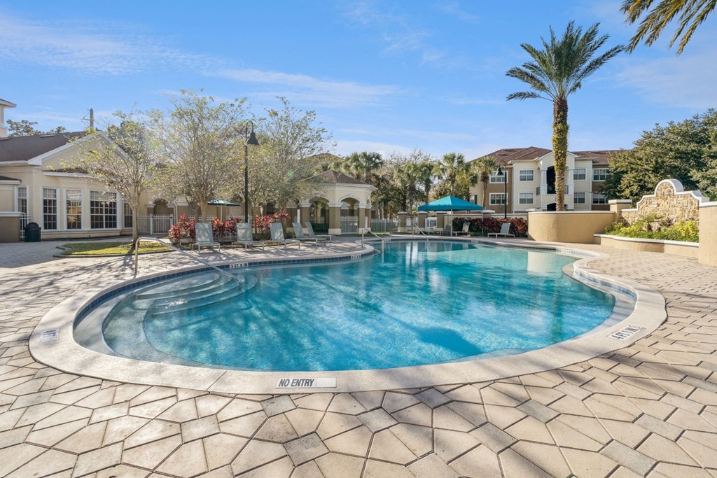 a swimming pool with palm trees and a building in the background at Grandeville on Saxon, Florida