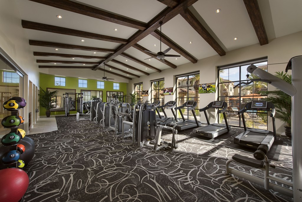 a gym with cardio equipment and weights on the floor