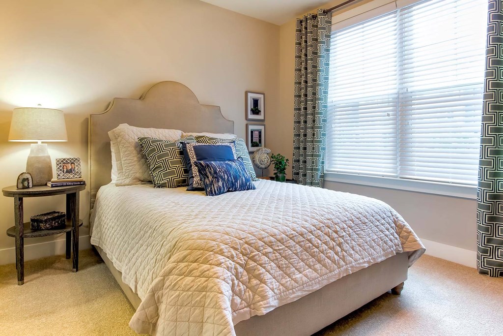 A bedroom with a large bed and a lamp on a side table at Wharf 7 Apartments, Charleston, SC