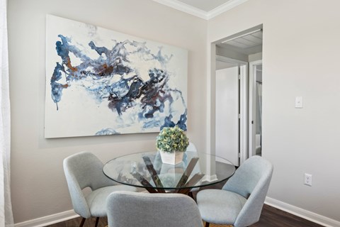 A modern dining room with a glass table and grey chairs.