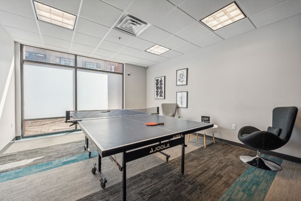 a game room with a ping pong table and chairs at Residences at Manchester Place in Manchester, New Hampshire