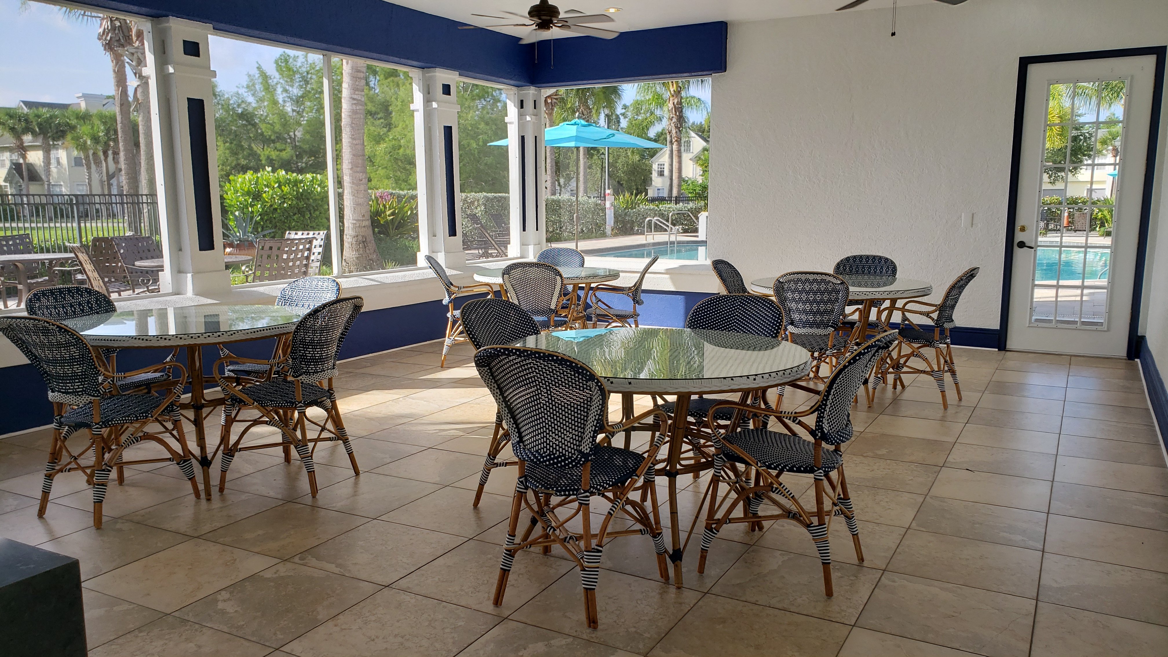 a dining area with tables and chairs and a pool in the background