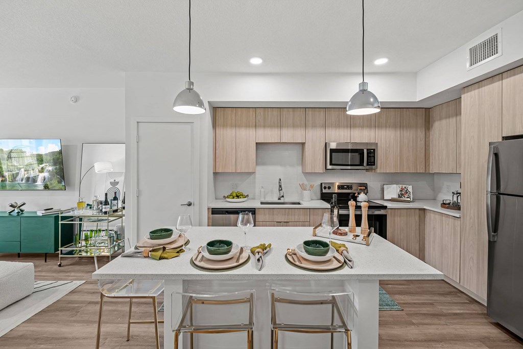 A modern kitchen with a dining table set for two.
