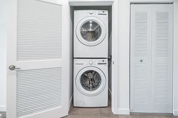 A white washing machine is in a white door.