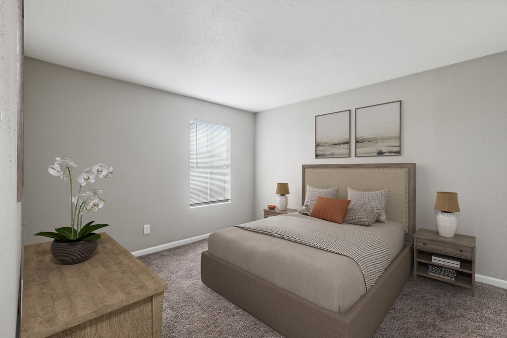 A bedroom with a large bed, a nightstand, and a table with a vase of flowers.