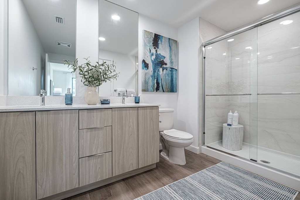 A bathroom with a toilet, sink, and a painting on the wall.