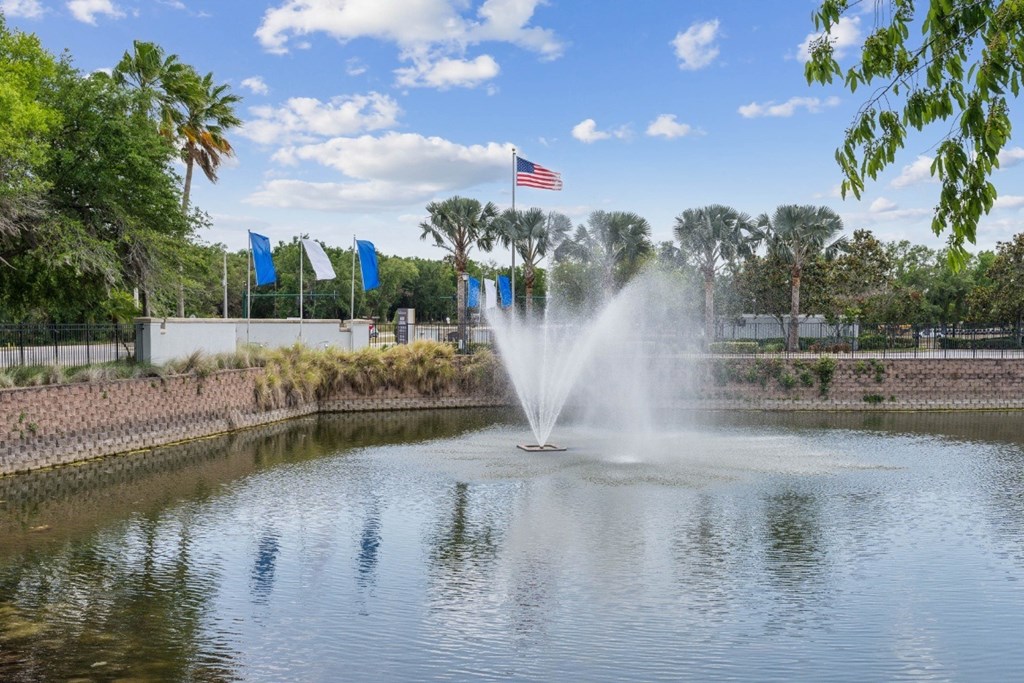 A fountain in the middle of a pond with the American flag in the background.