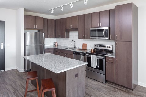a kitchen with stainless steel appliances and a marble counter top at Maven on Broadway Apartments, Rochester, Minnesota