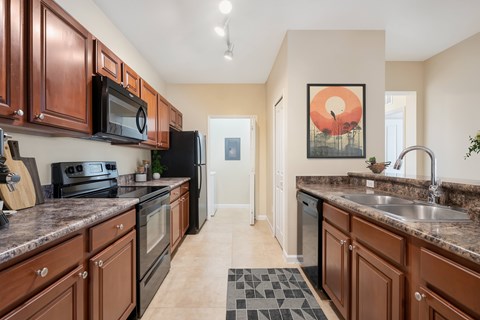 A kitchen with brown cabinets and a black refrigerator.